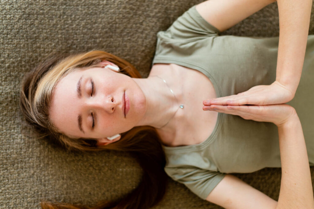 jovem-mulher-profissional-holística-meditando-em-casa-deitada-no-chao